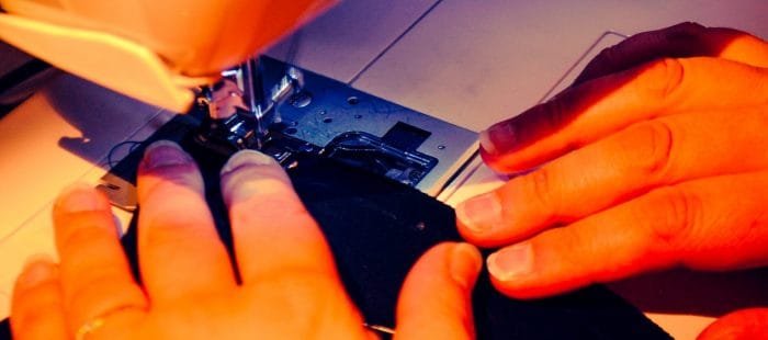 mani che cuciono con la macchina da cucire